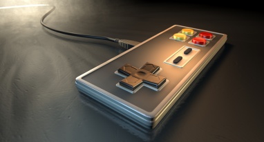 A regular vintage rectangular gaming controller with red and yellow buttons on an isolated dark spotlit studio background